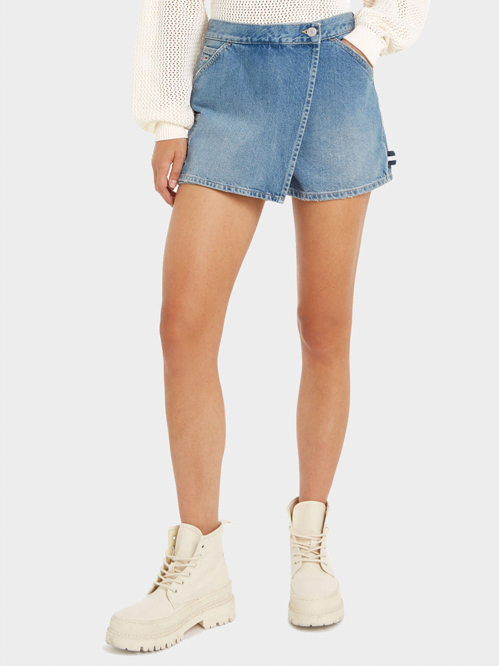 Lo skort Tommy Jeans è realizzato in denim rigido di cotone riciclato con chiusura a portafoglio, bottone, passante porta utensili, tasche ad angolo sul davanti, tasca portamonete, tasca laterale e du... 